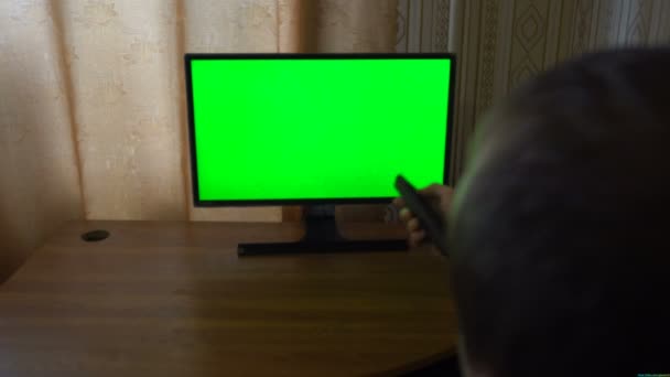 Мужская рука с ТВ дистанционное переключение каналов на зеленый экран ТВ точки зрения — стоковое видео