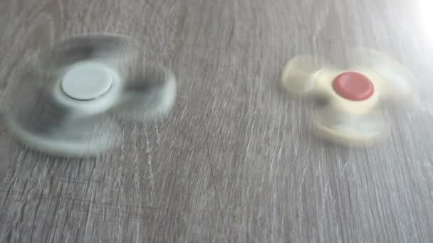 Two white hand spinner spinning on grey background or fidget spinners — Stock Video