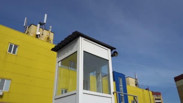 Cabine avec un haut-parleur sur le fond des bâtiments jaunes et bleus et le ciel — Video