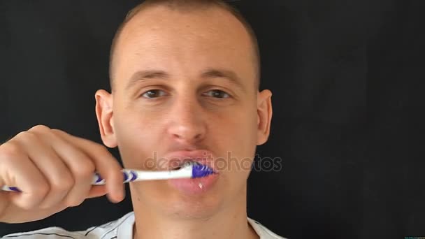 Hombre limpia los dientes sobre fondo negro — Vídeo de stock