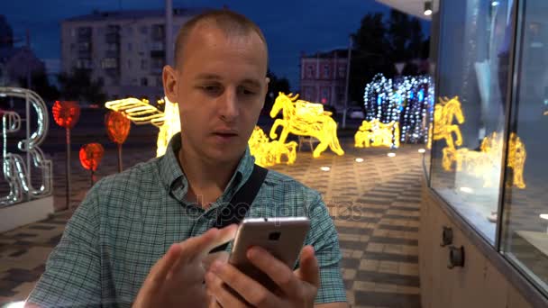 男子短信应用在智能手机上晚上在城市。英俊的年轻商业人使用智能手机微笑快乐穿着西装衬衫在户外。城市男性的专业人员，在他 20 多岁 — 图库视频影像