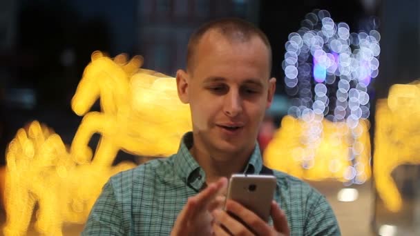 Homem SMS SMS usando aplicativo no telefone inteligente à noite na cidade. Bonito jovem homem de negócios usando smartphone sorrindo feliz vestindo camisa terno ao ar livre. Homem urbano profissional em seus 20 anos — Vídeo de Stock