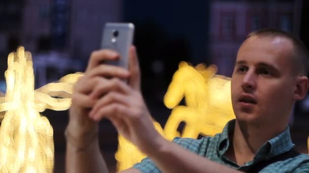 Ο άνθρωπος λήψη φωτογραφιών με την κάμερα του τηλεφώνου το βράδυ. Νεαρός casual λαμβάνοντας εικόνα με κάμερα του τηλεφώνου στο δρόμο — Αρχείο Βίντεο