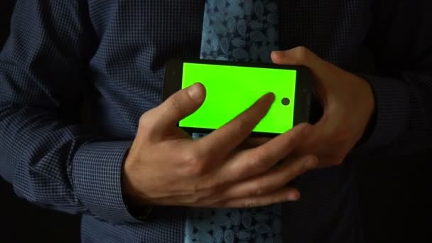 Man holds smartphone to camera with green screen — Stock Video