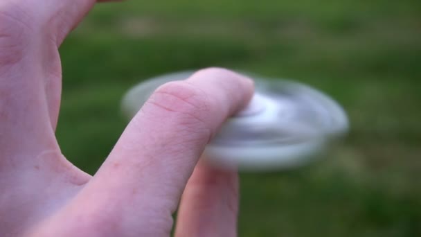 White hand spinner, or fidgeting spinner, rotating on childs hand — Stock Video