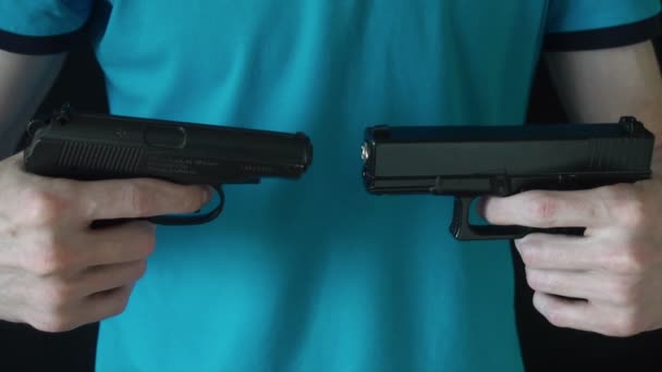 Fiatal férfi tartja kezében két fekete puskáját — Stock videók