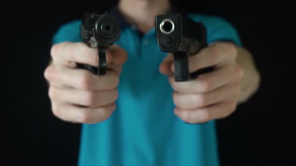 Den unge mannen leder två svart pistol på kameran — Stockvideo