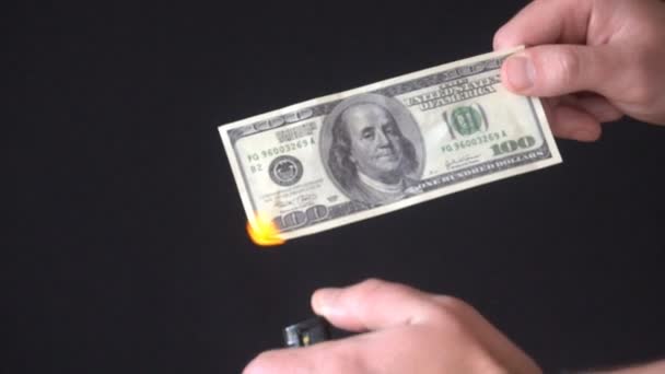 Hand hält 100 Dollar auf schwarzem Hintergrund und zündet sie mit einem Feuerzeug an. Hand hält brennende hundert Dollar — Stockvideo