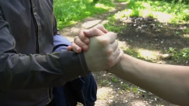 Рукопожатие двух молодых людей в лесу — стоковое видео