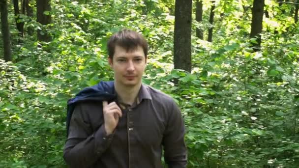 Un giovane uomo d'affari attraversa il bosco in una giornata di sole — Video Stock