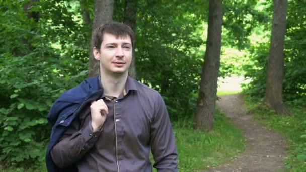 Um jovem homem de negócios atravessa a floresta em um dia ensolarado — Vídeo de Stock