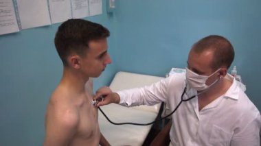 Doktor steteskopla hastanın ciğerlerini dinliyor.