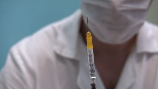 Doctor in mask with syringe in hand preparing for the shot — Stock Video