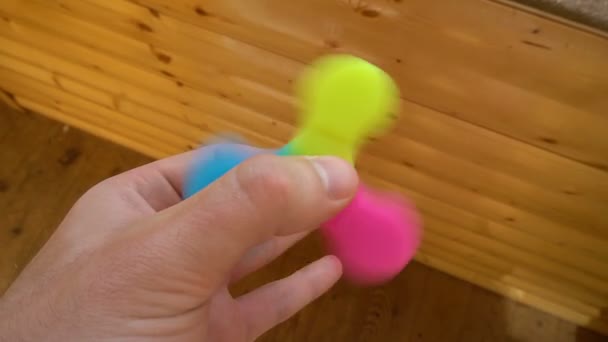 Játék a színes izeg-mozog tárcsával. Toy a spinner a kezében — Stock videók