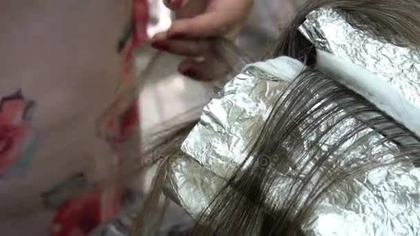 Женщина у парикмахера, стилист красит волосы — стоковое видео