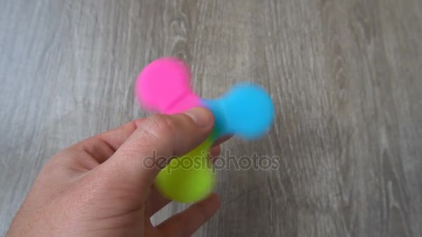 Spiel mit dem bunten Fidget Spinner. Spielzeugschleuder in der Hand — Stockvideo