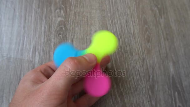 Spiel mit dem bunten Fidget Spinner. Spielzeugschleuder in der Hand — Stockvideo