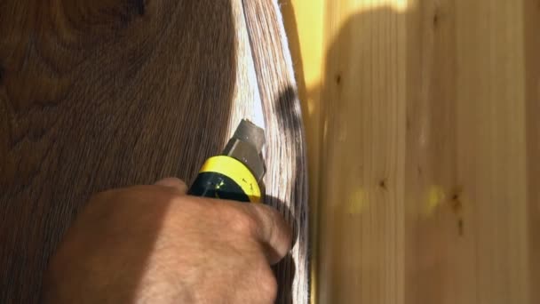 Der Arbeiter schneidet das Linoleum mit einem Werkzeugmesser ab, indem er den Linoleumboden einbaut — Stockvideo