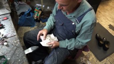 Ayakkabıcı iş gününün sonunda kazanılan parayı sayar.