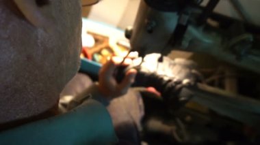 Ayakkabıcı ayakkabıları makineye dikiyor.