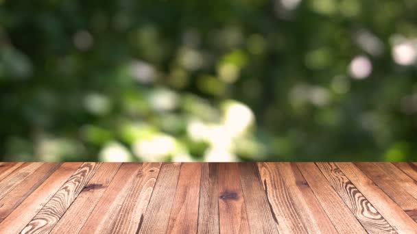 Perspectief hout en bokeh licht achtergrond. product weergave sjabloon. Houten tafelblad op vervagen natuurlijk groene blad achtergrond verplaatsen — Stockvideo