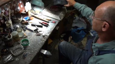 Ayakkabı tamircisi elektrikli ocağın musluklarını ısıtır ve ayakkabılarına yapıştırır.