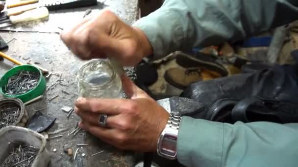 De schoenmaker zet zijn bril op en begint zijn werk — Stockvideo