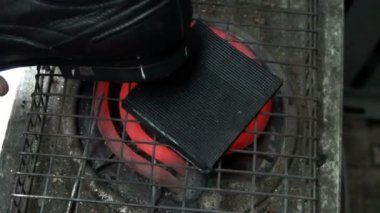 Ayakkabı tamircisi elektrikli ocağın musluklarını ısıtır ve ayakkabılarına yapıştırır.