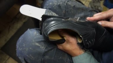 Shoemaker atölyede ayakkabıyı tamir ederken 4k ayakkabıların musluklarını kesti.