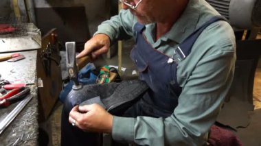 Shoemaker atölyede ayakkabıyı tamir ederken 4k topuk kapağını topuğa çiviler.