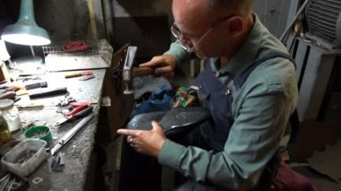 Shoemaker atölyede ayakkabıyı tamir ederken 4k topuk kapağını topuğa çiviler.