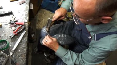 Shoemaker atölyede ayakkabıyı tamir ederken 4k topuk kapağını topuğa çiviler.