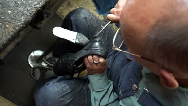 Sapateiro reparando um sapato na oficina 4k cortar as torneiras nos sapatos — Vídeo de Stock
