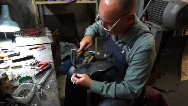 Shoemaker naprawia but w warsztacie 4k gwóźdź czapkę pięty do pięty — Wideo stockowe
