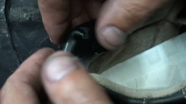 De schoenmaker stokken een zwart lederen patch op sneakers — Stockvideo