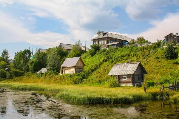 North village rosyjski. Letni dzień, rzeka, stare chaty na wybrzeżu. — Zdjęcie stockowe