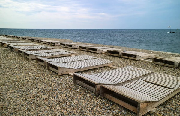 Boş çakıl plajı üzerinde boş şezlonglar satırları