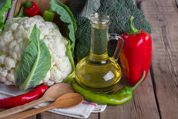 Брокколи, цветная капуста, перец и оливковое масло на деревянном фоне — стоковое фото