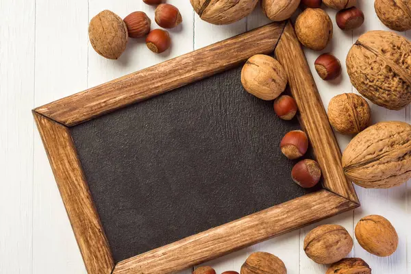 Schultafel Und Nüsse Auf Weißem Holztisch — Stockfoto