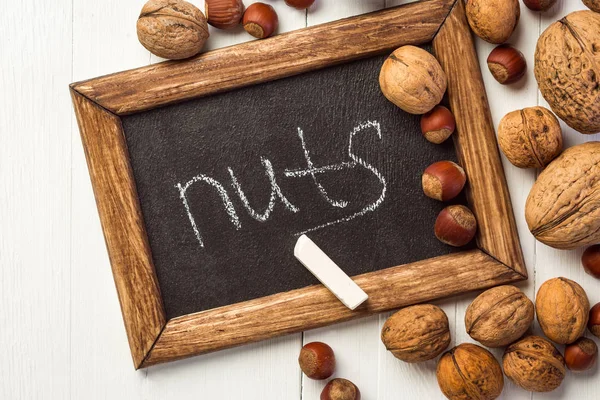 Schultafel Und Nüsse Auf Weißem Holztisch — Stockfoto