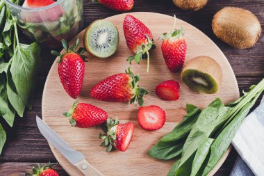 Ispanak, muz, kivi ve ahşap arka plan üzerinde çilek smoothies hazırlamak