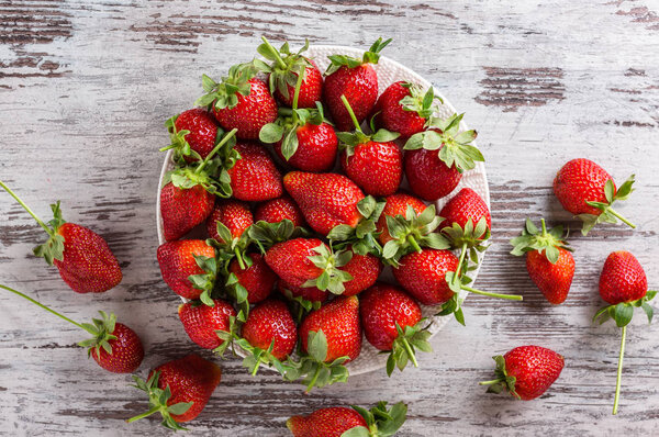 strawberries in a plate on a gray wooden table, fresh strawberries on a table, seasonal fruits