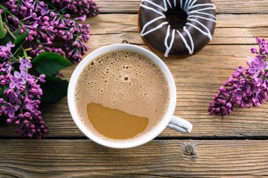 ahşap bir masa, çörek ve Lila, Bahar günü bir buket sütlü kahve