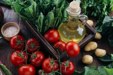 Tablo, sebze ve bitkisel yağ, domates, salatalık ve Yeşiller ve ahşap bir masa üzerinde bir ahşap kutu içinde ıspanak