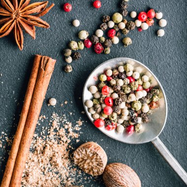 Karanlık bir arka planda baharat karışımı, biber, hindistan cevizi, anason yıldızı ve tarçın çubuğu.