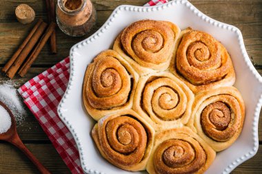 Tahta bir masada tatlı tarçınlı rulo, ev yapımı kekler.