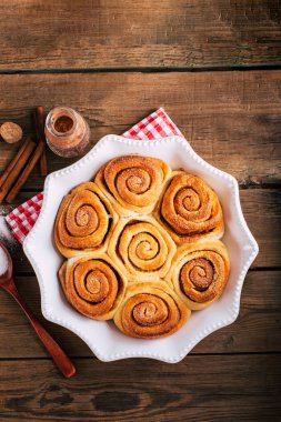 Tahta bir masada tatlı tarçınlı rulo, ev yapımı kekler.