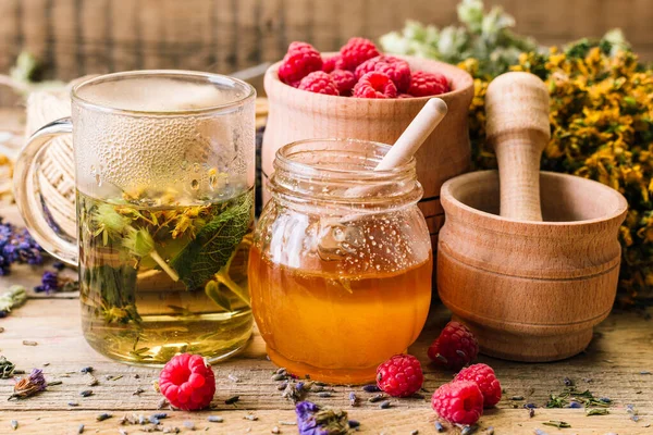 Chá de ervas, mel e framboesas em uma mesa de madeira, medicina alternativa, Ayurveda, flores secas — Fotografia de Stock