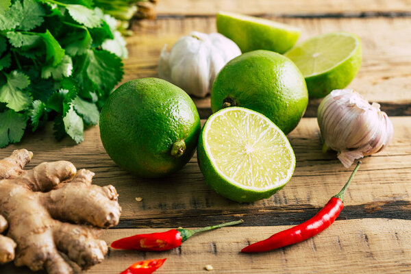 Thai food, lime, ginger, chili pepper, garlic and coriander on a wooden background