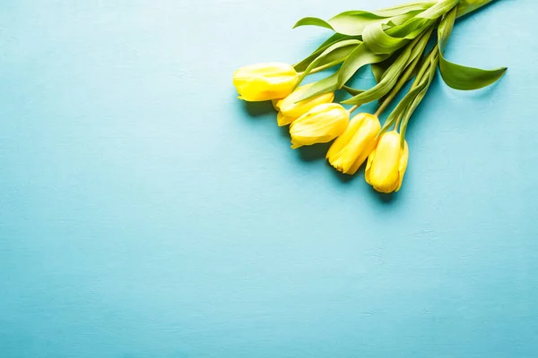 Жовті тюльпани на синьому дерев'яному фоні, букет квітів, горизонтальний банер, простір для копіювання — стокове фото